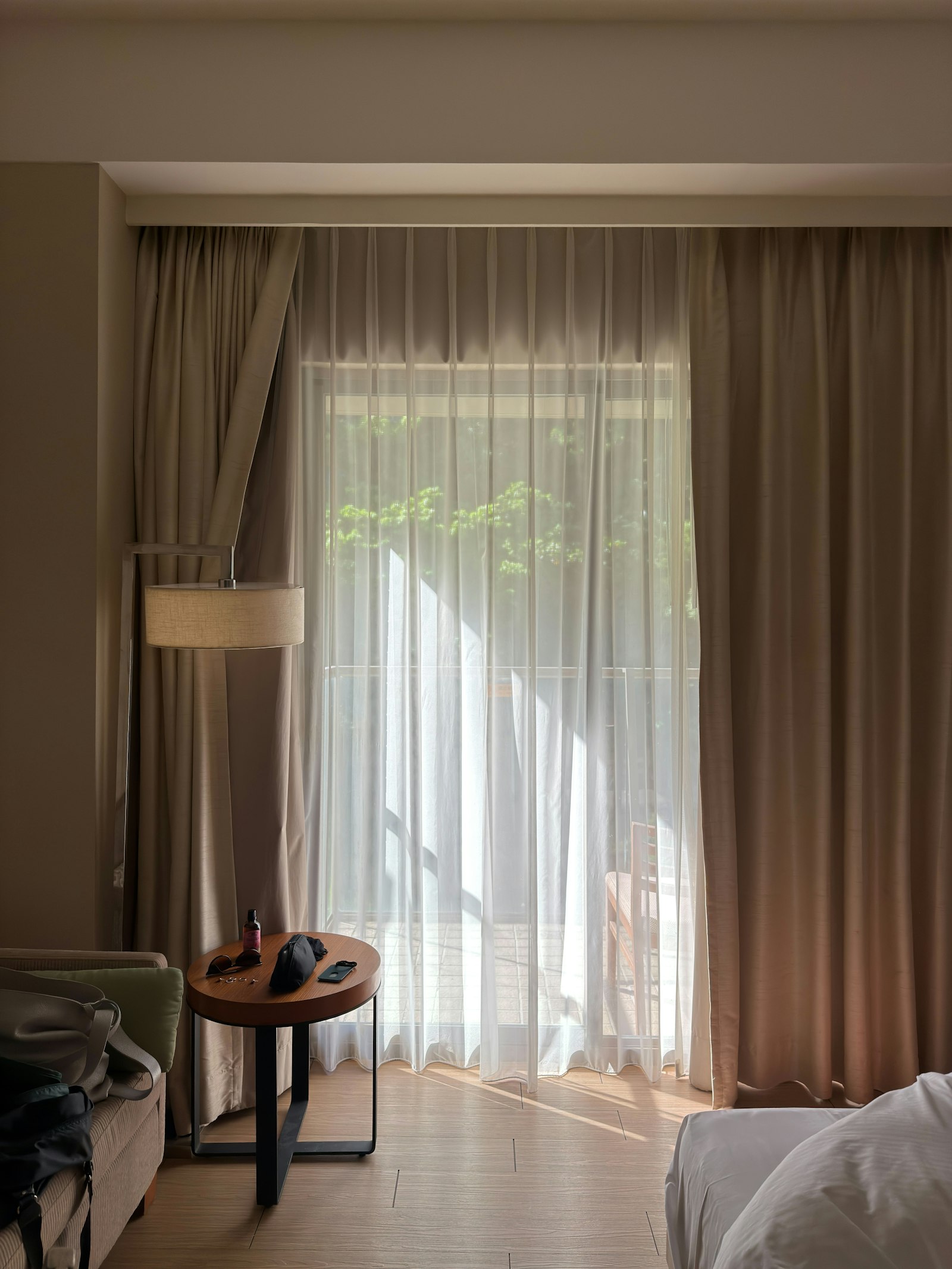 Zimmer 3: Sonnenlicht fällt durch den Vorhang, Beistelltisch und Stehlampe am Fenster.